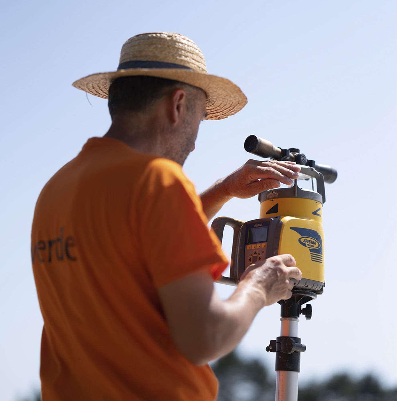 Medewerker van idverde stelt een laserwaterpasinstrument in op statief voor een landmeetkundige controle.