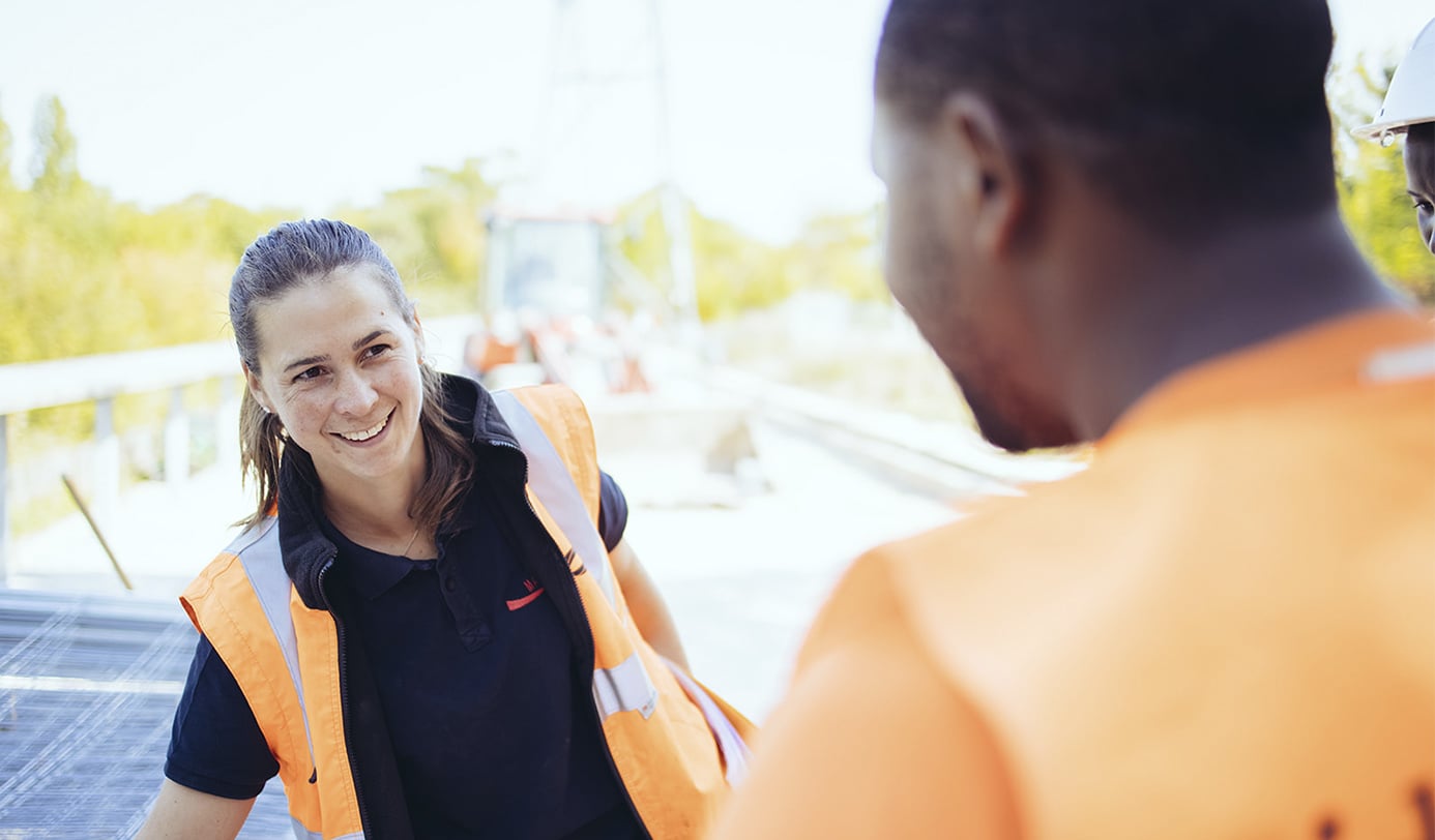 Medewerkers in veiligheidshesjes overleggen op een buitenlocatie tijdens groenwerkzaamheden.