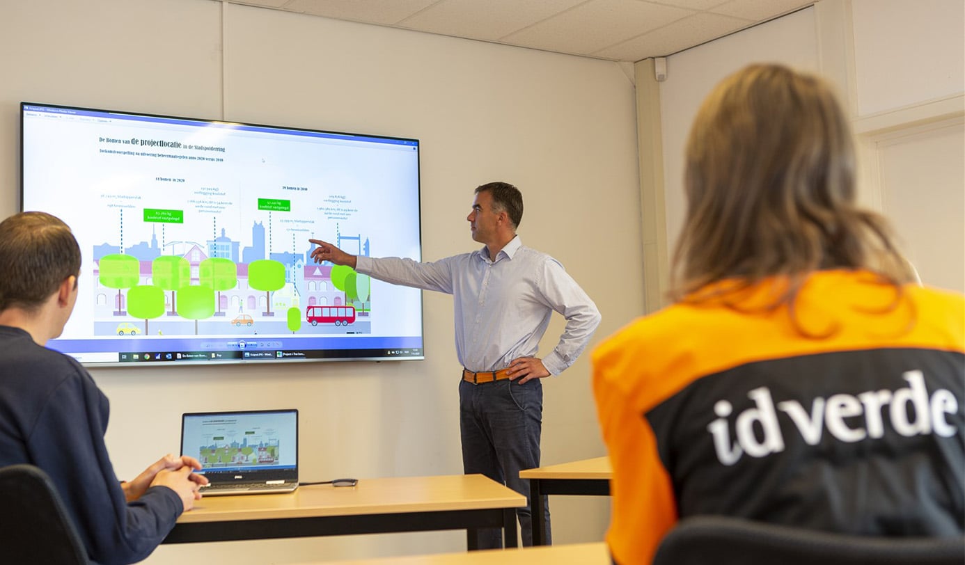 Medewerker idverde presenteert bomenonderzoek en beheerplan aan collega's op scherm tijdens overleg.