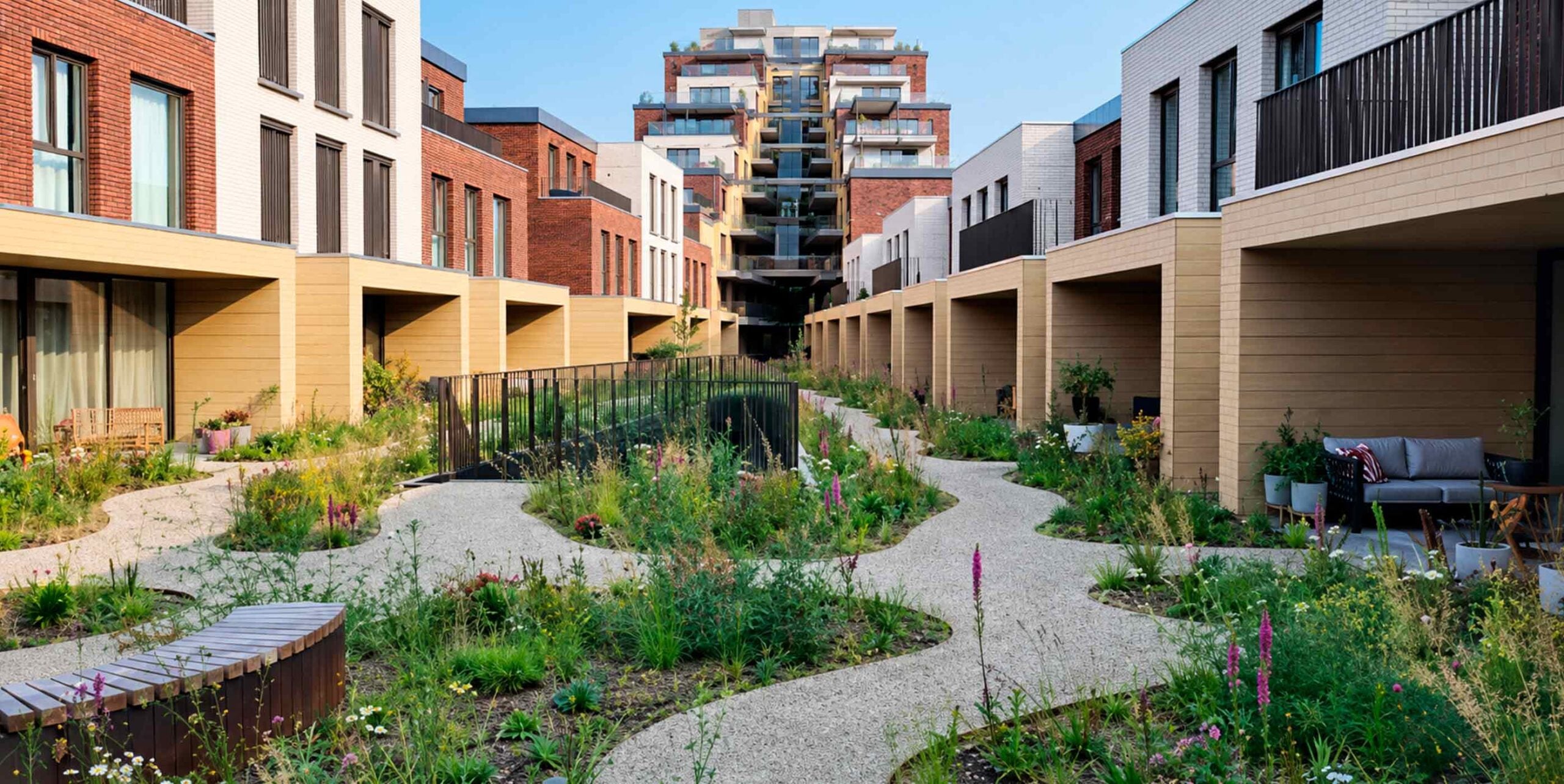 Slingerend grindpad met bloemrijke beplanting in binnentuin tussen woningen in stedelijke woonwijk.