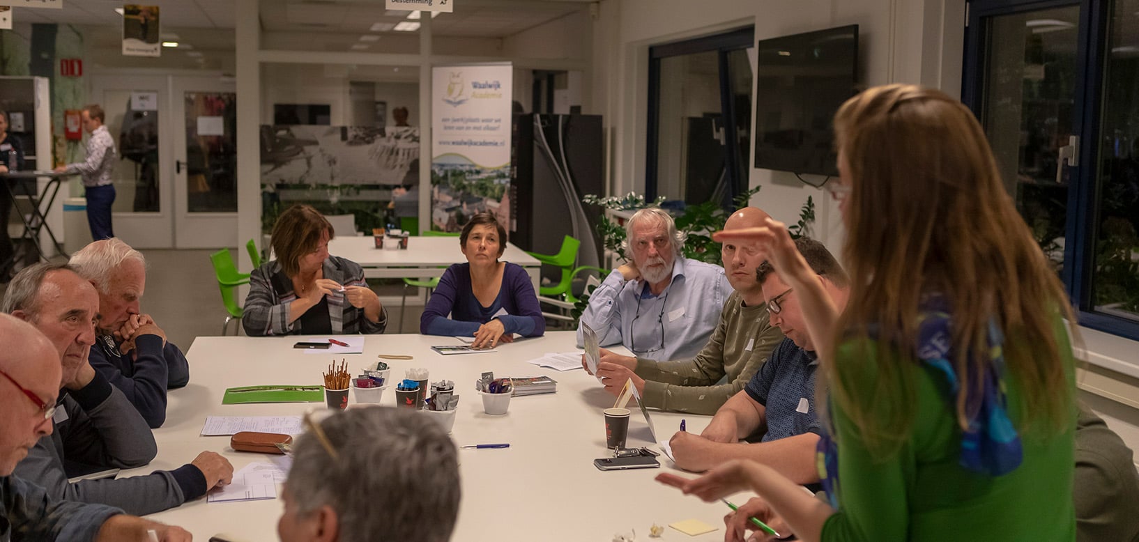 Medewerker geeft toelichting aan bewonersgroep tijdens overlegbijeenkomst over groenplanning.