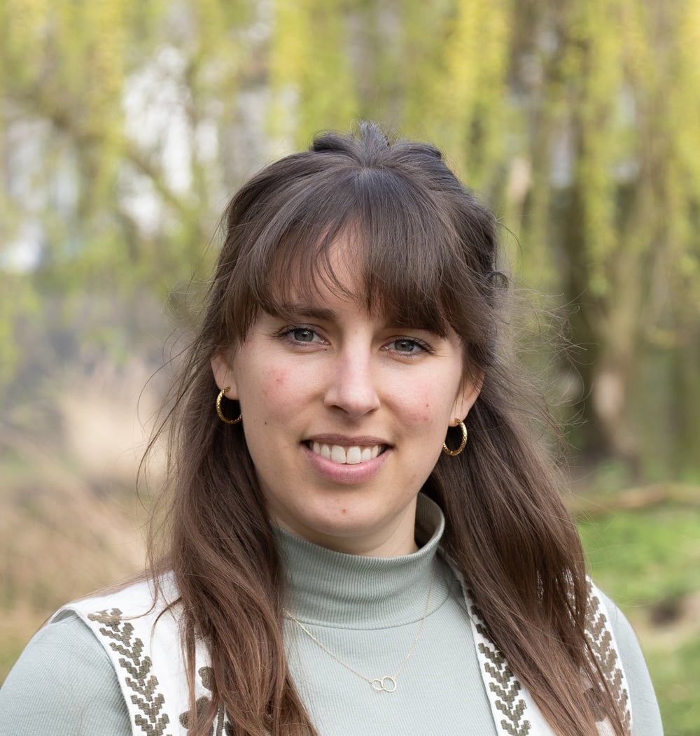 Anna Herlings, adviseur ecologie bij idverde, lachend in een groene buitenomgeving.