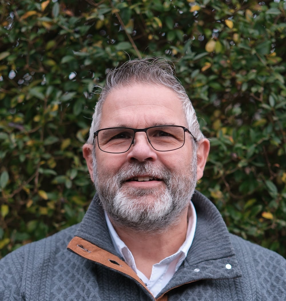 Portret van Arjan Dans, vestigingsmanager bij idverde, voor een groene heg.