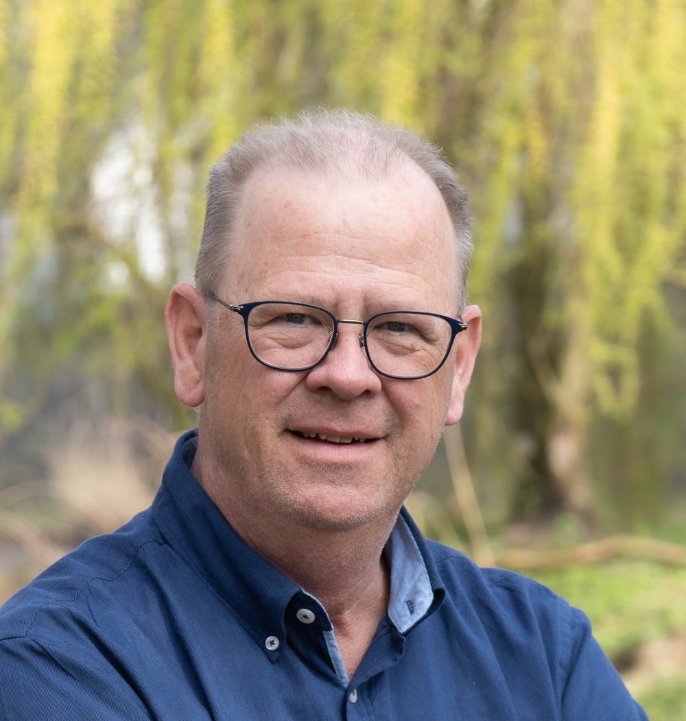 Arjan Raaijmakers, adviseur Engineering & Contracten bij idverde, poseert buiten voor een wilg.