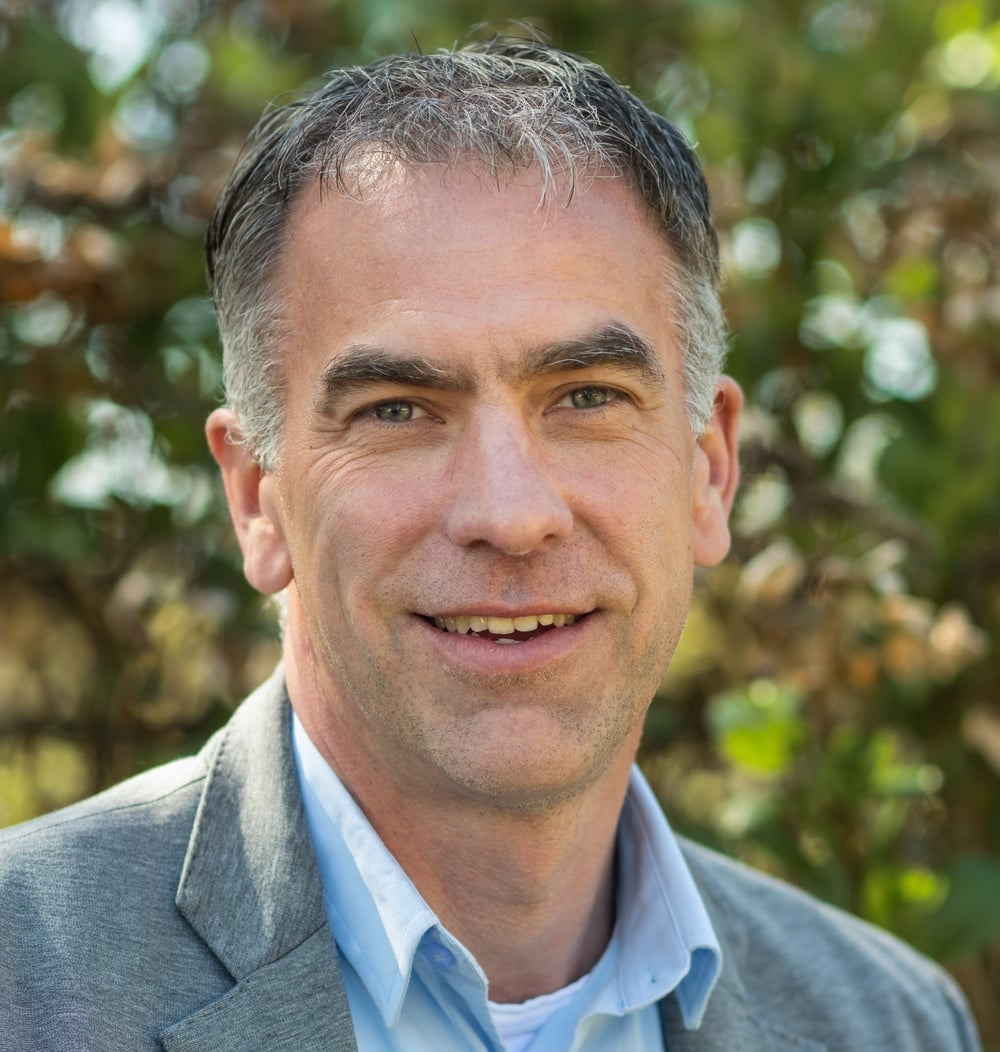 Arnold Meulenbelt, Business Developer Bomendienst bij idverde, portretfoto met groene begroeiing op de achtergrond.
