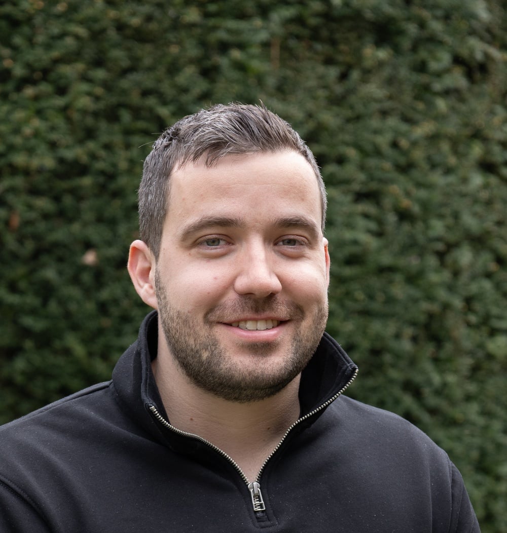 Medewerker van idverde, Daan van Bergen, poseert voor een groene heg.