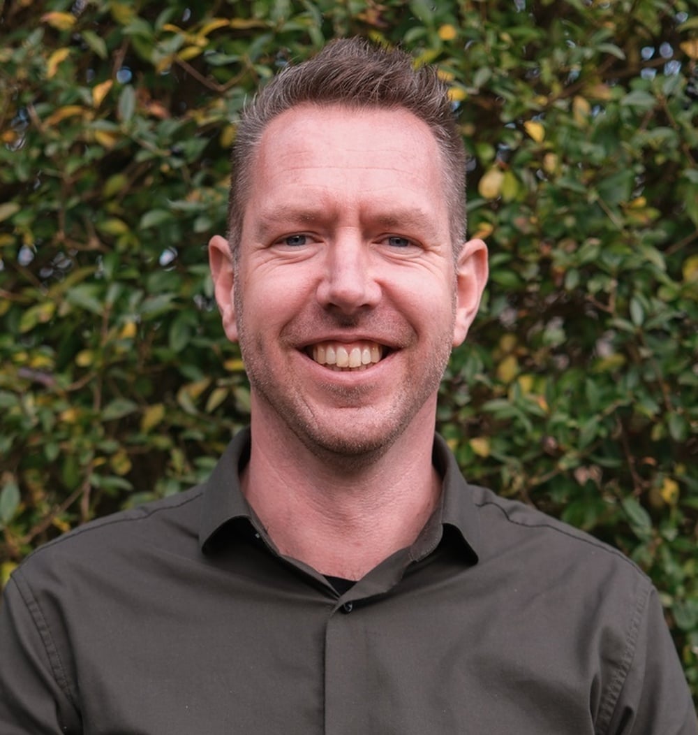 Erik van Veelen, vestigingsmanager bij idverde, poseert voor een groene heg.