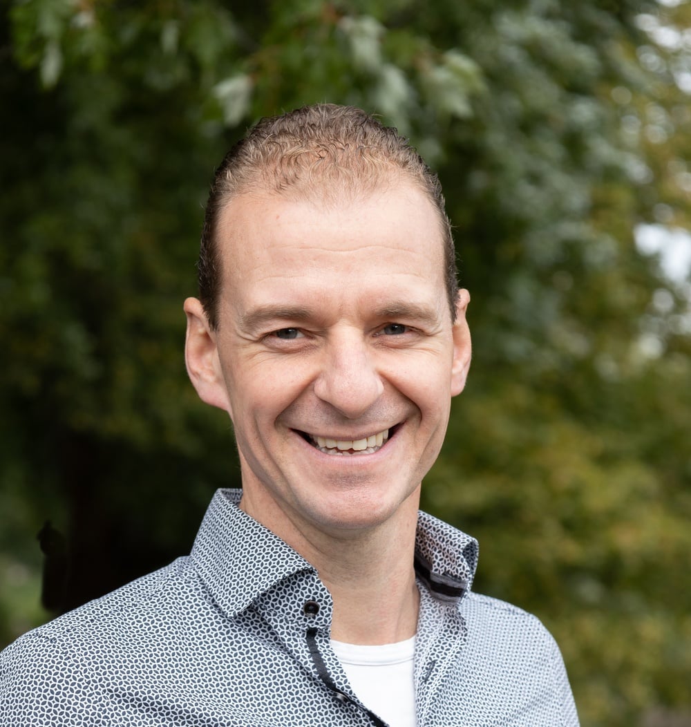 Frank Molin, senior projectleider bij idverde, lachend op een portretfoto buiten met groen op de achtergrond.