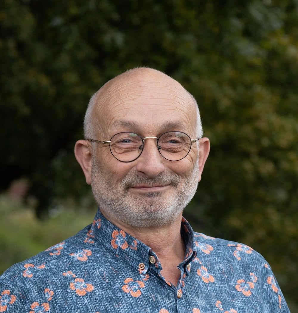 Portret van Hans van der Heijden, Teamleider Ontwerp & Inrichting, met groene bomen op de achtergrond.