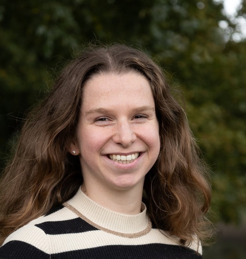 Jaimie van der Vleut, adviseur ecologie bij idverde, met groene begroeiing op de achtergrond.