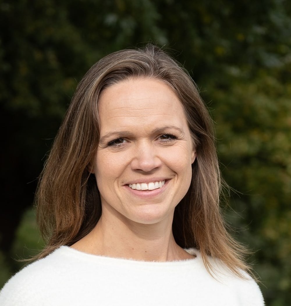Portretfoto van Jannie Vos, Manager Strategie en Projecten bij idverde, met groene begroeiing op de achtergrond.