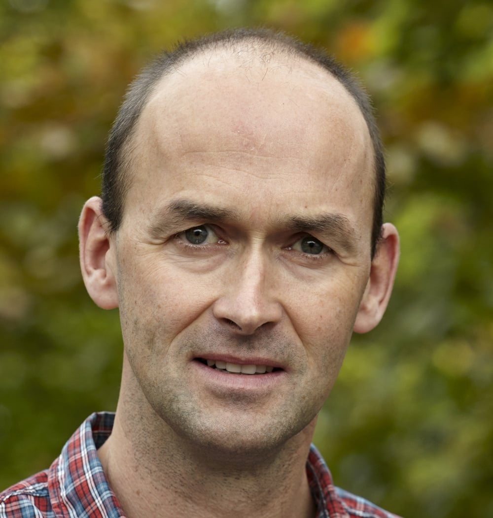 Portret van Jeroen Denissen, seniorprojectleider bij idverde, buiten met groene achtergrond.