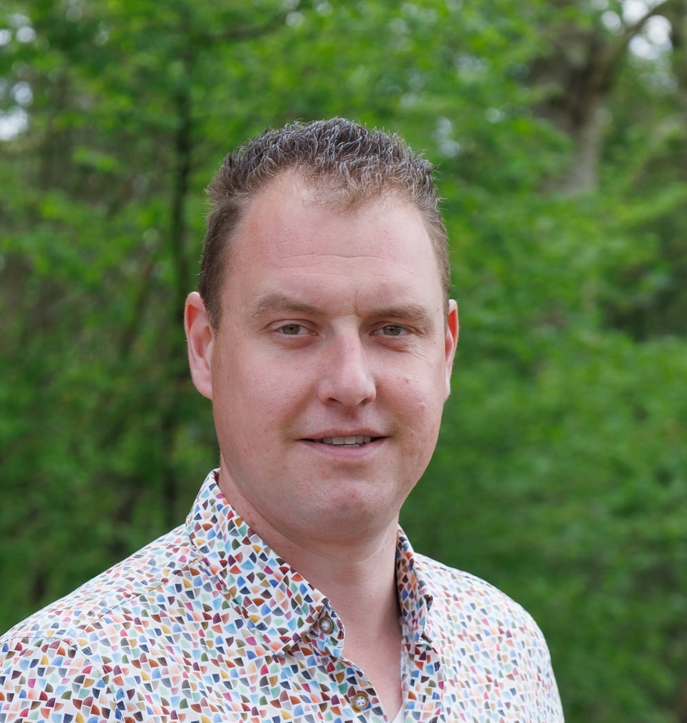 Portret van Jeroen van Erve, vestigingsmanager i.o., voor groene achtergrond met bomen.
