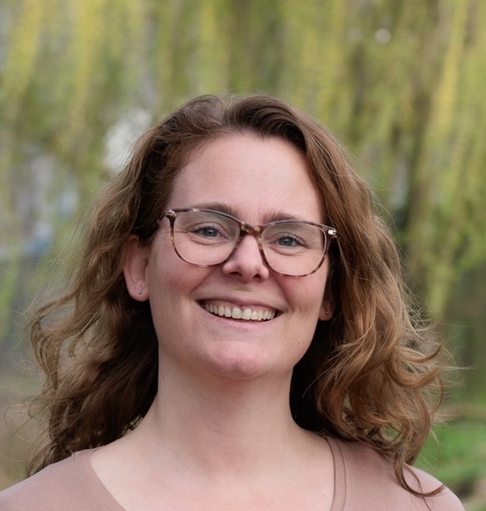 Portret van medewerker Jirina Verkuijlen-Quist, adviseur Spelen bij idverde, buiten voor groene achtergrond.