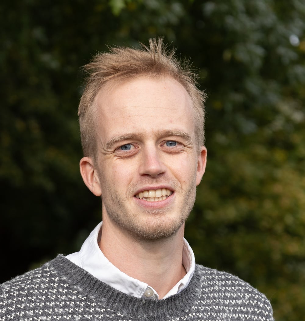 Job Kwakernaak, adviseur Geo-informatie bij idverde, poseert glimlachend voor groene begroeiing.