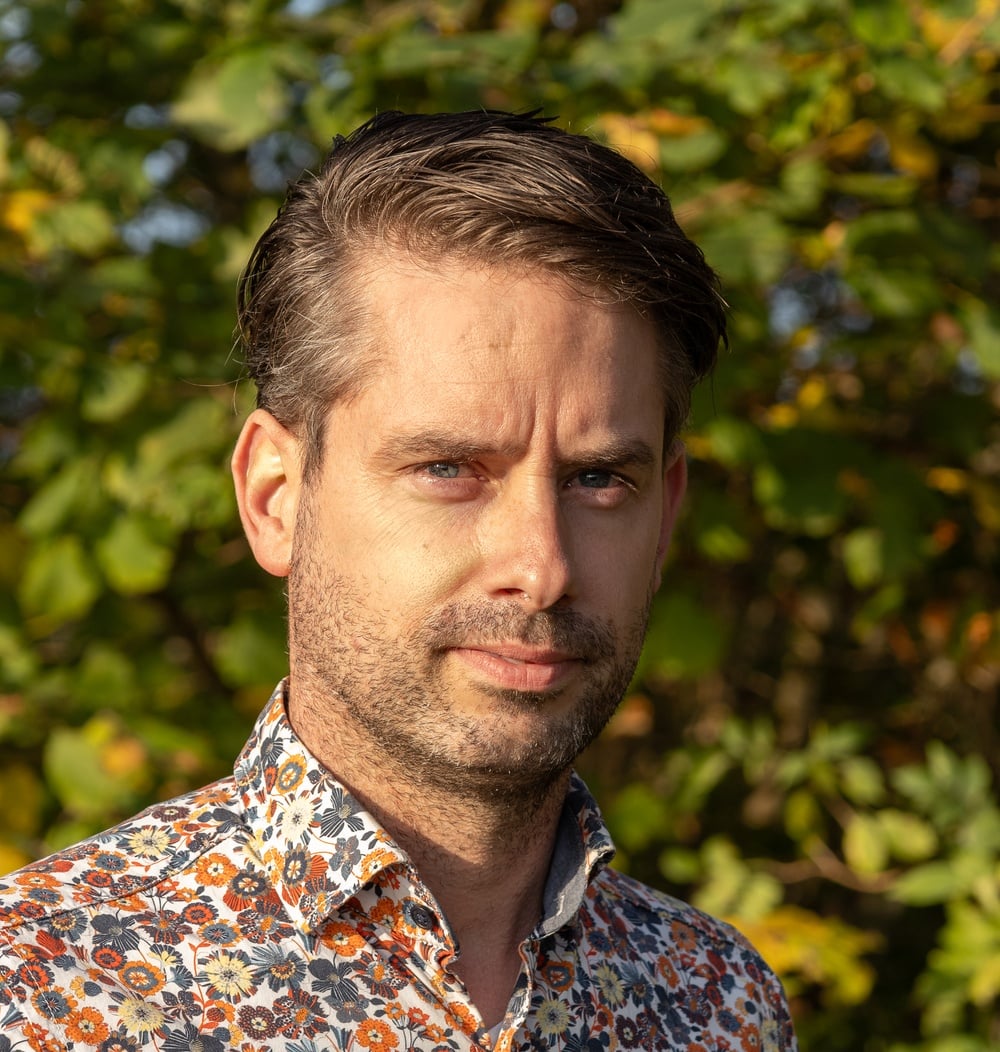 Portret van Joost Duin, projectleider bij idverde, buiten met groene begroeiing op de achtergrond.