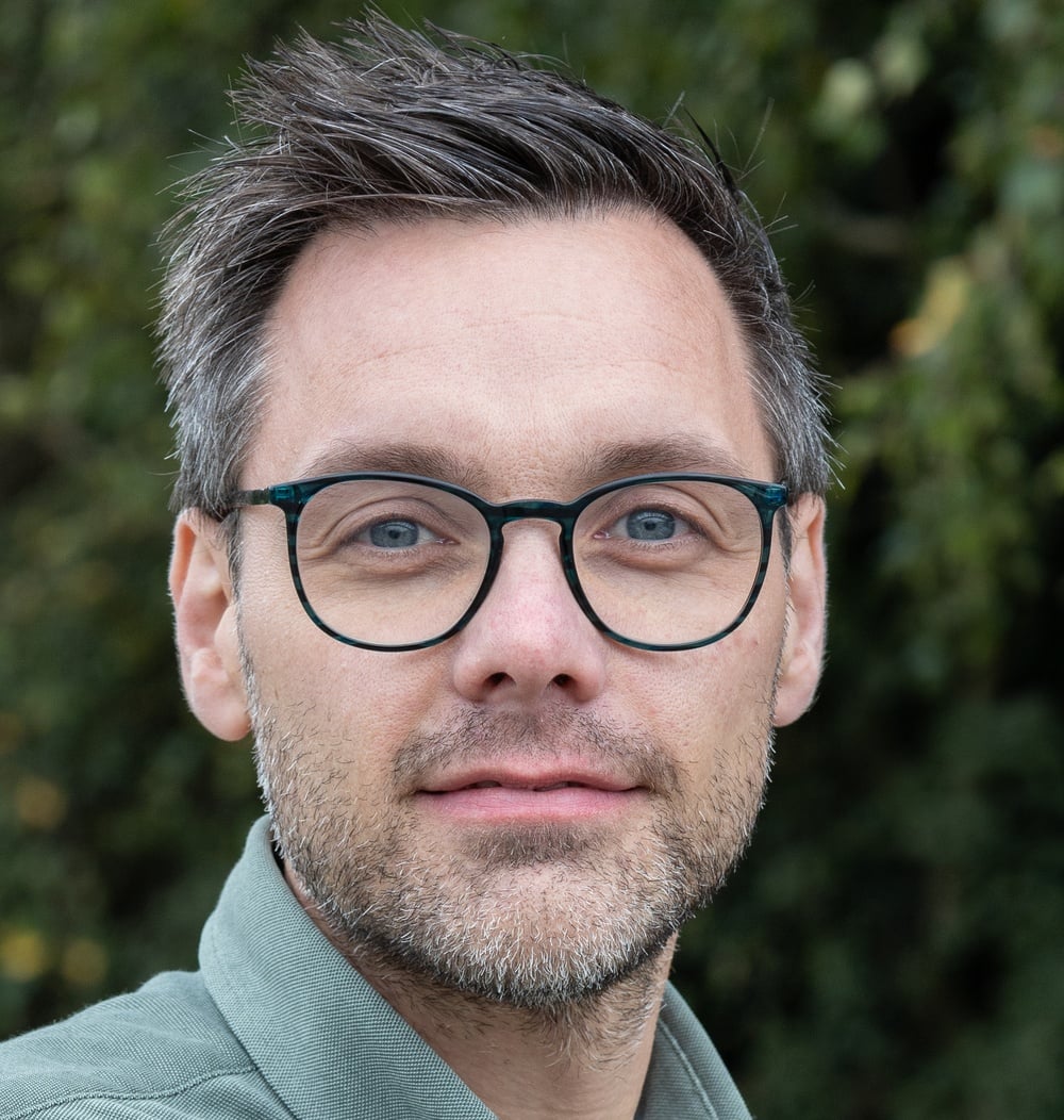 Joost IJsseldijk, senior werkvoorbereider bij idverde, portretfoto met groene achtergrond.