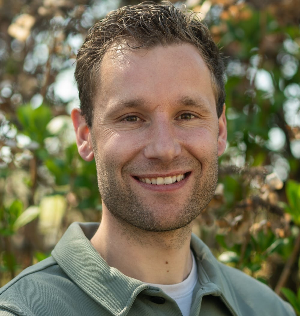 Joost Leerkes, projectleider DutchTrig & Boomtechnisch Advies, glimlachend voor groen struikgewas.