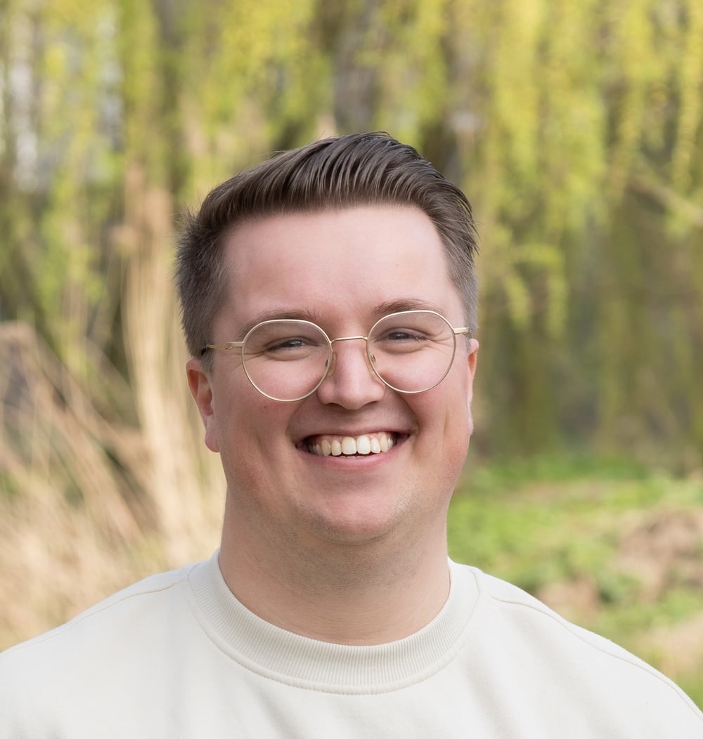 Portret van Joppe Oonk, Adviseur Engineering & Contracten bij idverde, buiten met groen op de achtergrond.