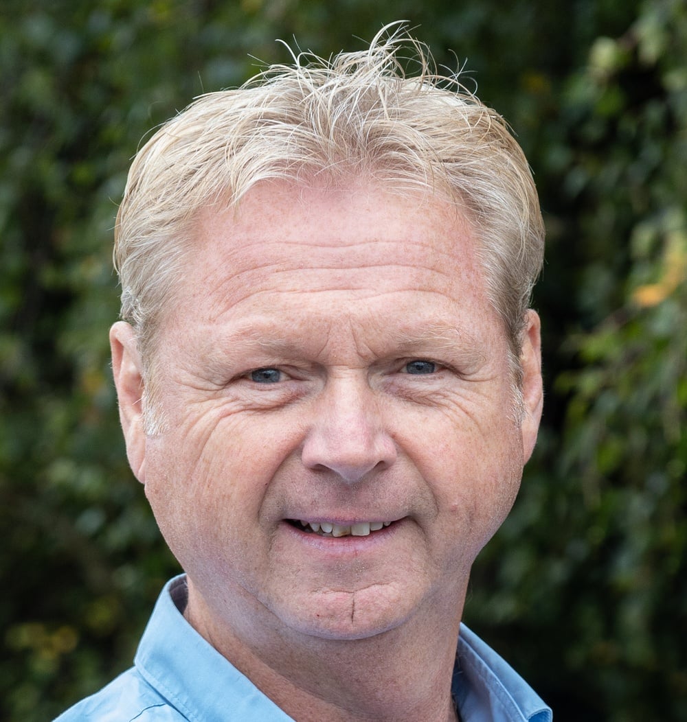 Klaas Jager, vestigingsmanager bij idverde, portretfoto met groene achtergrond.