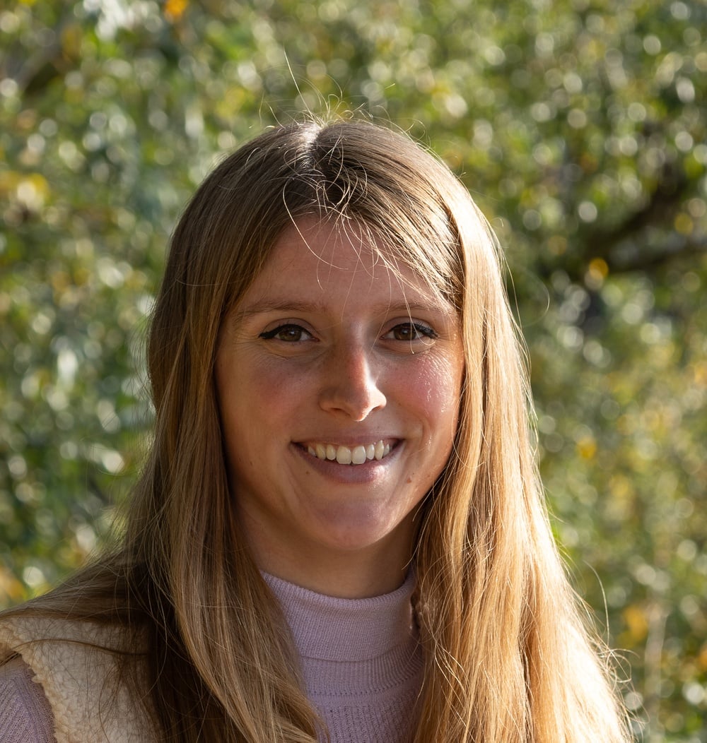Laura Kooijman, adviseur ecologie bij idverde, glimlachend voor groene bomen.