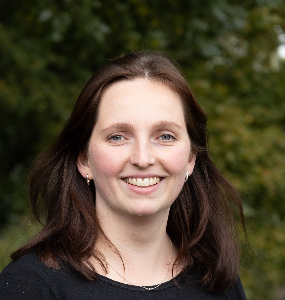 Maartje Staal, adviseur Ecologie bij idverde, glimlachend voor de camera met groen op de achtergrond.
