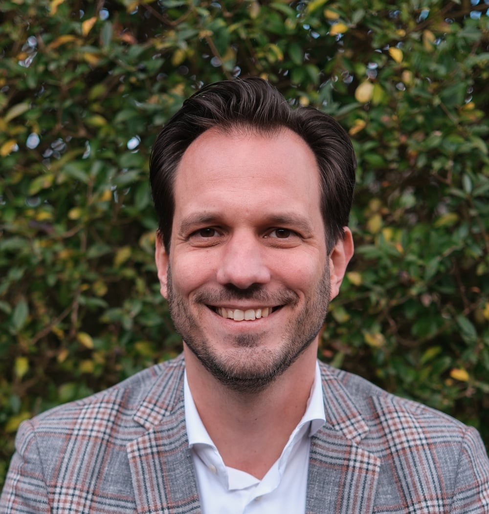 Marc Redegeld, Head of HR bij idverde, portretfoto voor een groene heg.