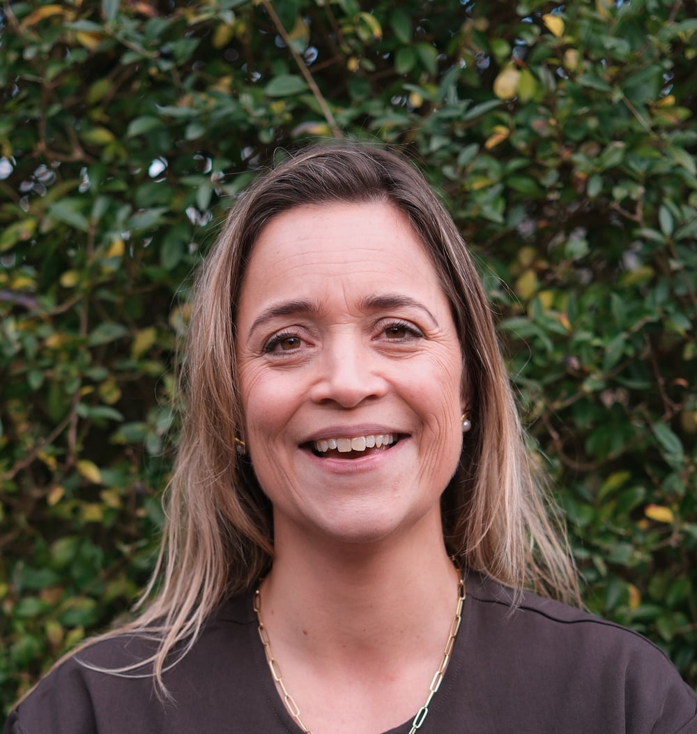 Mascha Maas, Head of Commerce bij idverde, lachend voor een groene heg.