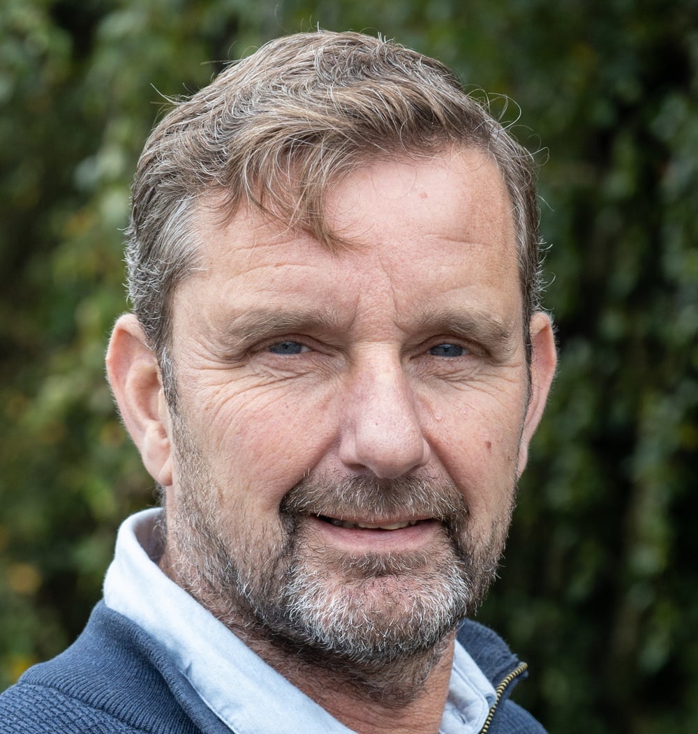 Portret van Michael Schriemer, senior projectleider bij idverde, met groene beplanting op de achtergrond.