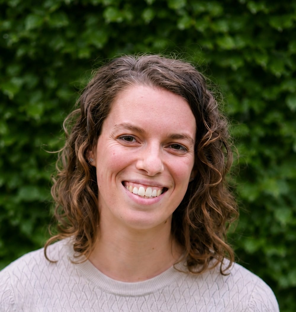 Michelle Bindels, boomtechnisch adviseur bij idverde, poseert voor een groene heg.