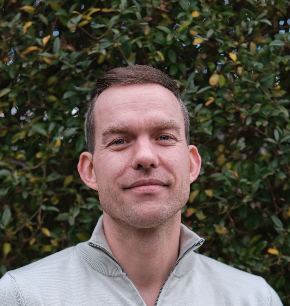 Michiel Cox, vestigingsmanager bij idverde, poseert voor een groene heg.