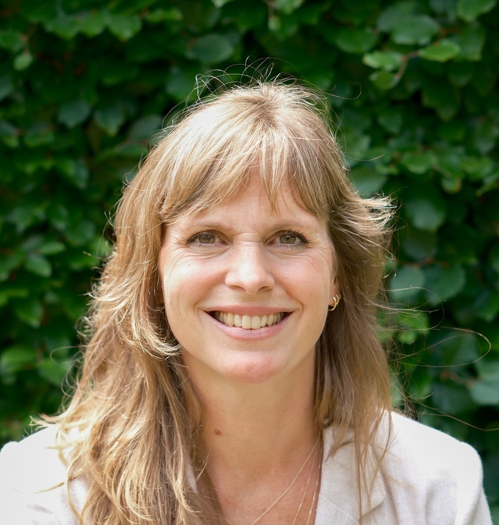 Portret van Mirthe Donker, adviseur bij idverde, voor een groene haag.