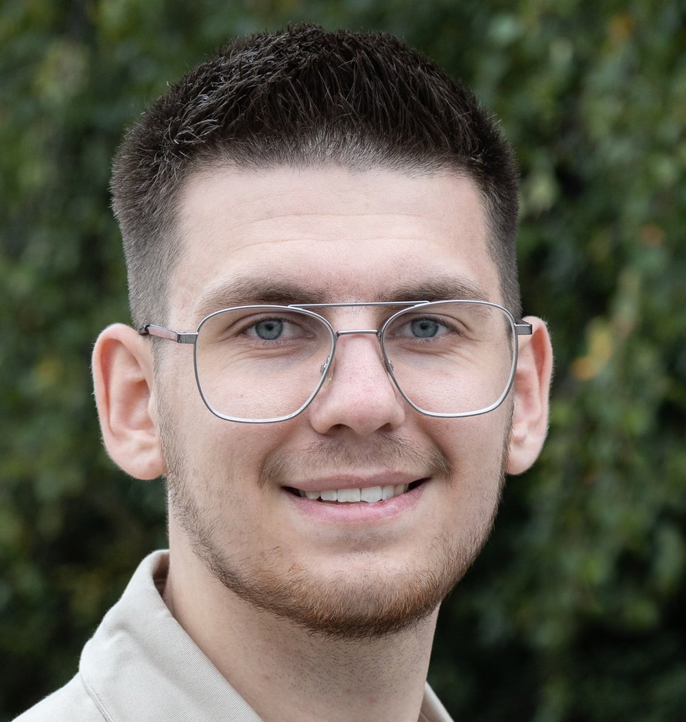 Portretfoto van medewerker Noah Bahnerth, werkvoorbereider i.o. bij idverde, met groene beplanting op de achtergrond.