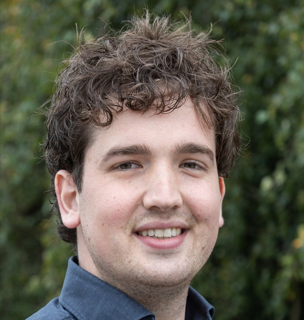 Peet Lokker, contractmanager bij idverde, glimlacht voor de camera met groene beplanting op de achtergrond.