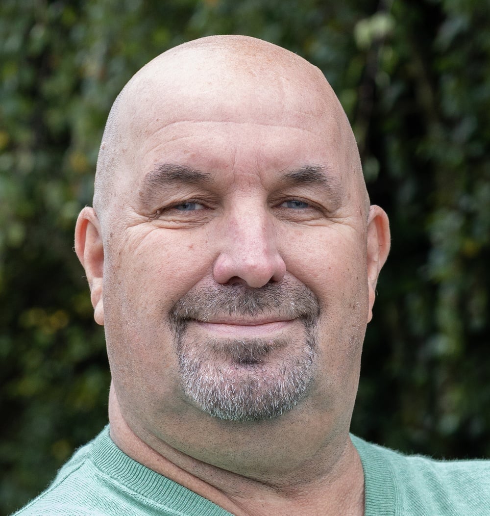 Peter Haksteen, projectleider bij idverde, portretfoto met groene beplanting op de achtergrond.