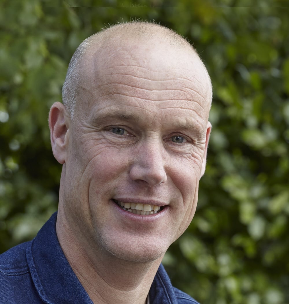 Rob van Dreumel, projectleider ETT bij idverde, poseert lachend voor groene begroeiing.