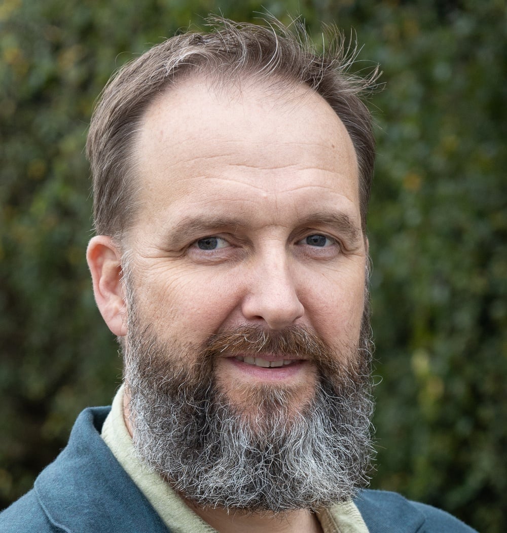 Portret van Ron Schraven, Manager International Business Development bij idverde, voor een groene heg.