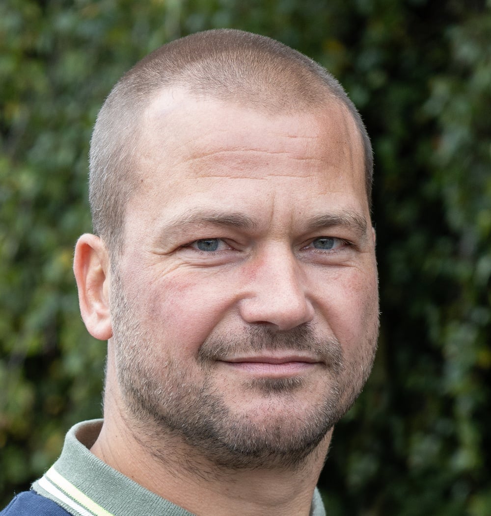 Tom Wolters, projectleider ETT bij idverde, poseert voor een groene heg.