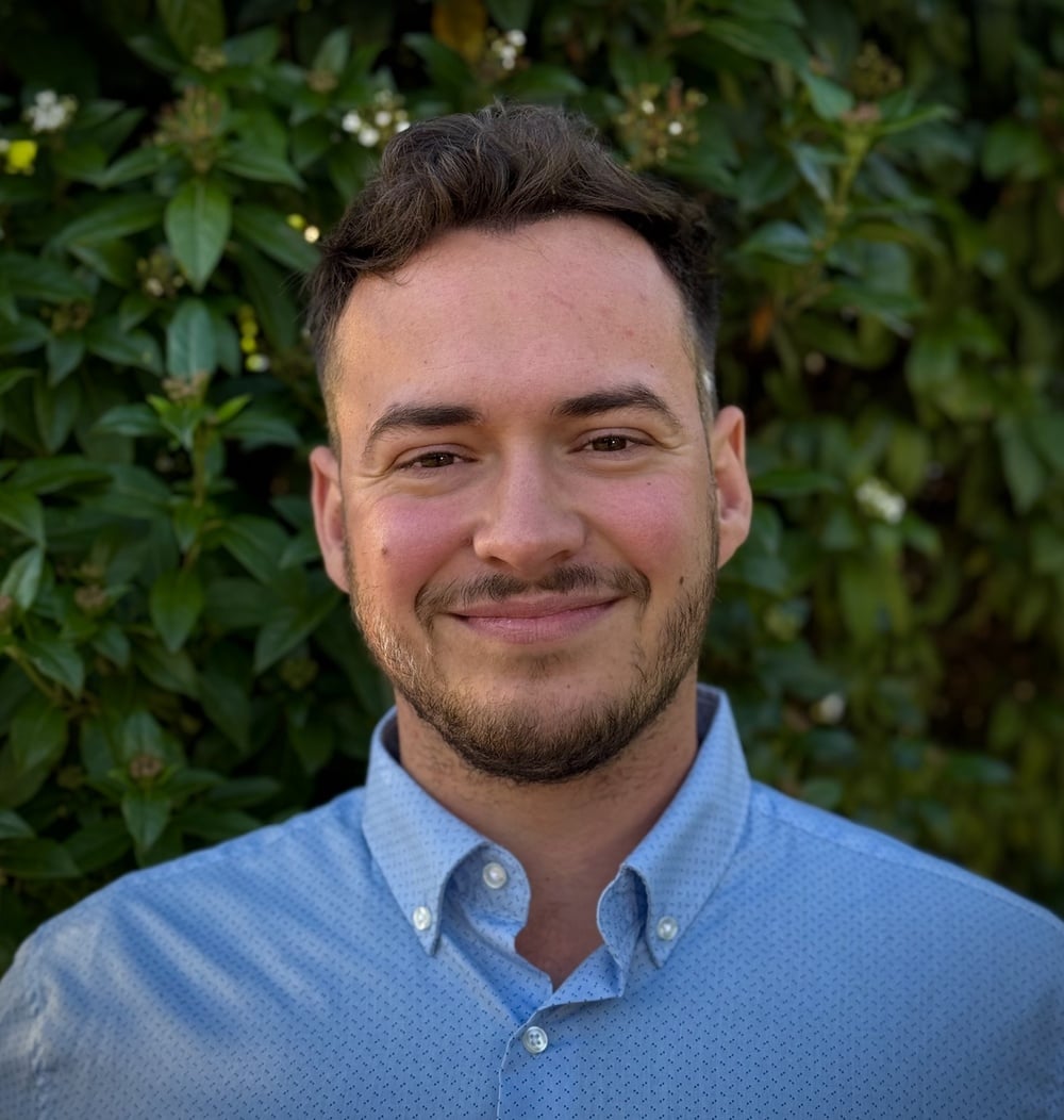 Wouter Breman, projectleider i.o. bij idverde, portretfoto voor een groene heg.