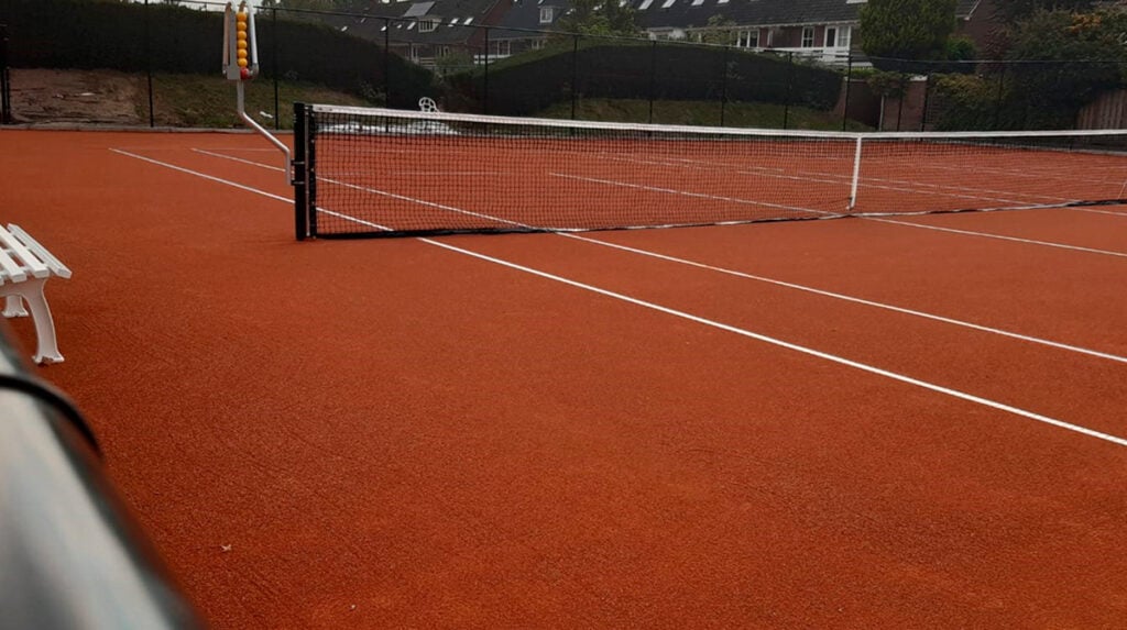 Nieuw aangelegde gravel tennisbaan met net op sportpark Molenbeke.