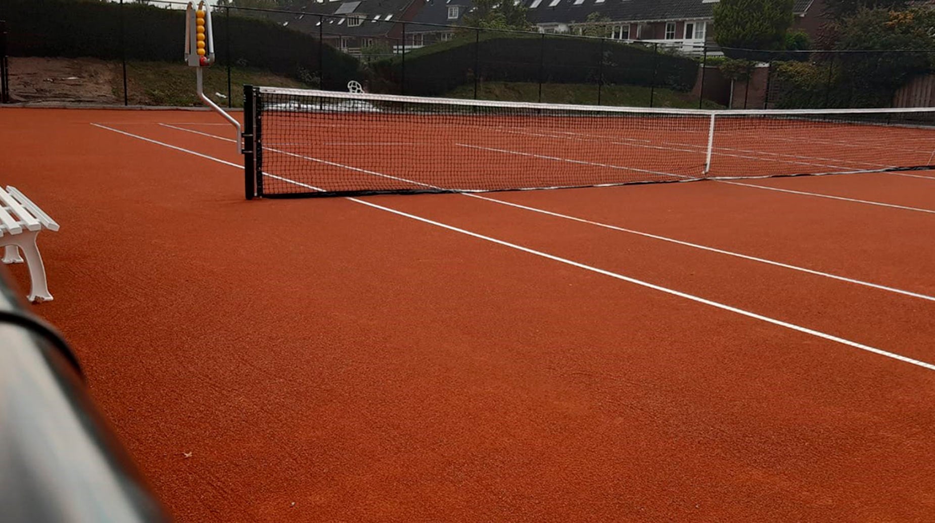 Nieuw aangelegde gravel tennisbaan met net op sportpark Molenbeke.