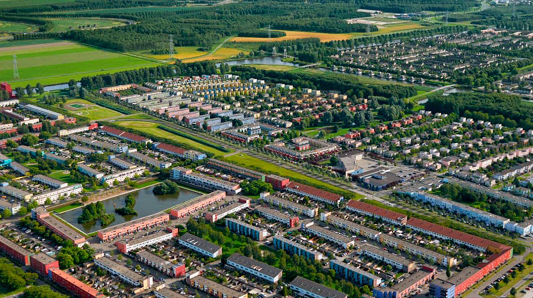 Luchtfoto van woonwijk met groenstructuur, waterpartijen en omliggend landschap.