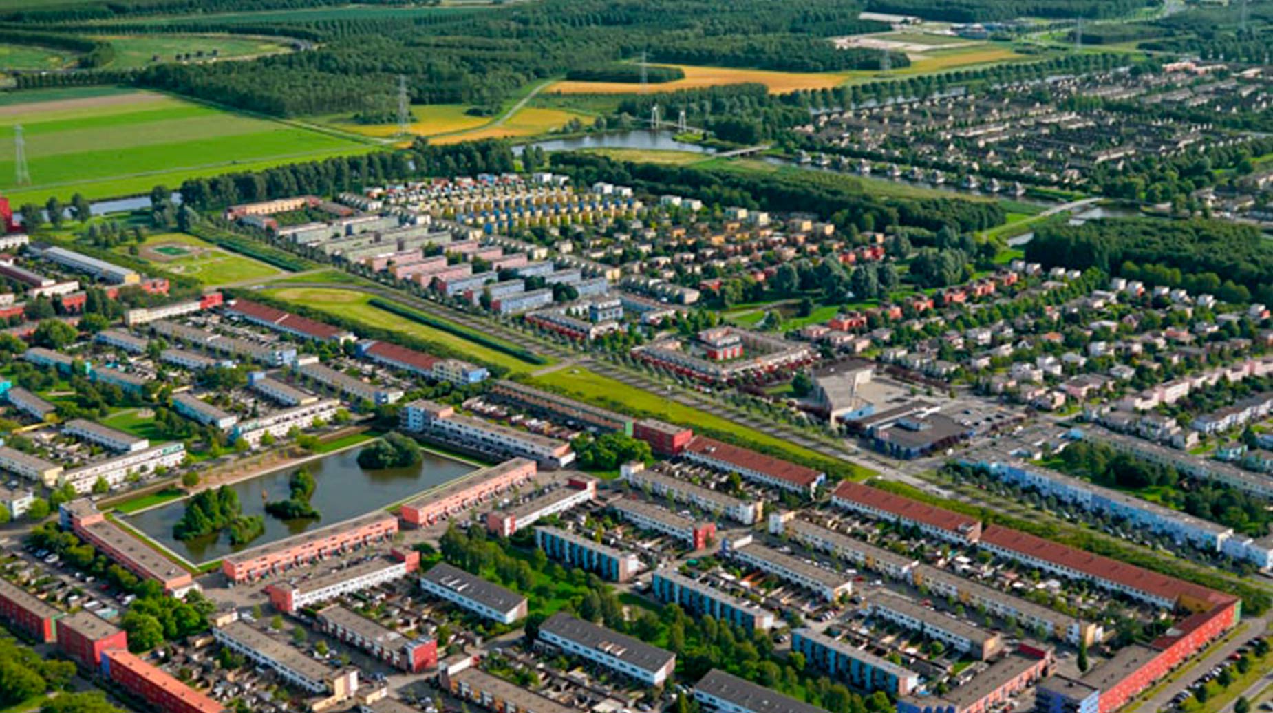 Luchtfoto van woonwijk met groenstructuren, waterpartijen en omliggend landelijk gebied.