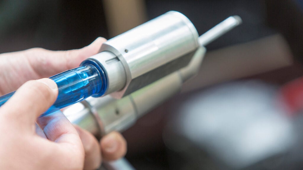 Medewerker sluit een injectienaald aan op metalen apparatuur voor boombehandeling.
