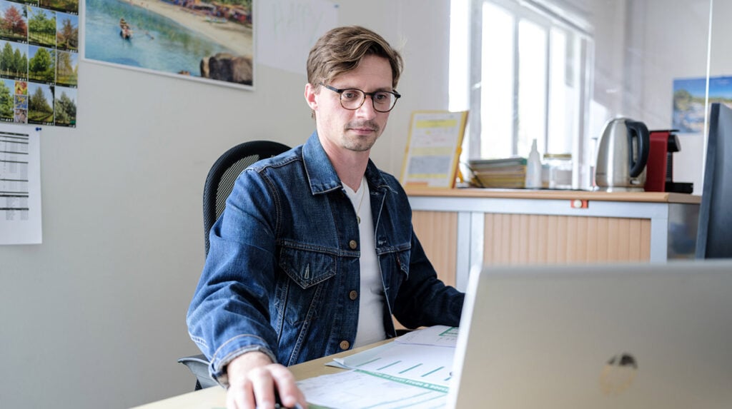 Medewerker werkt op kantoor achter laptop aan planning van groenonderhoud.