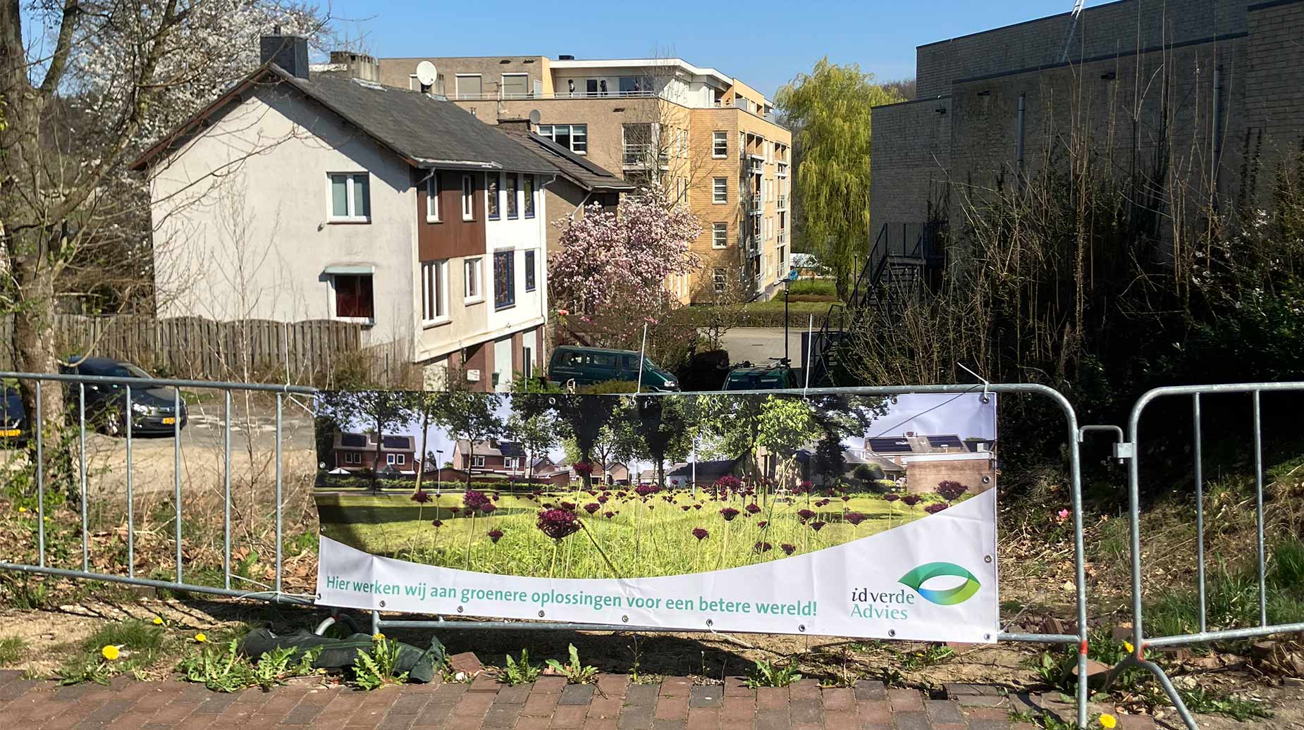 Bouwhek met idverde Advies-banner over herinrichting van een braakliggend terrein in een woonwijk.