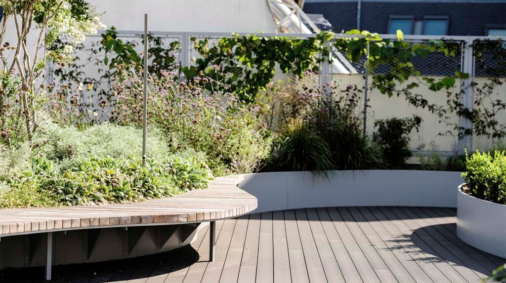 Daktuin met houten zitbank, plantenbakken en beplanting op een terras.