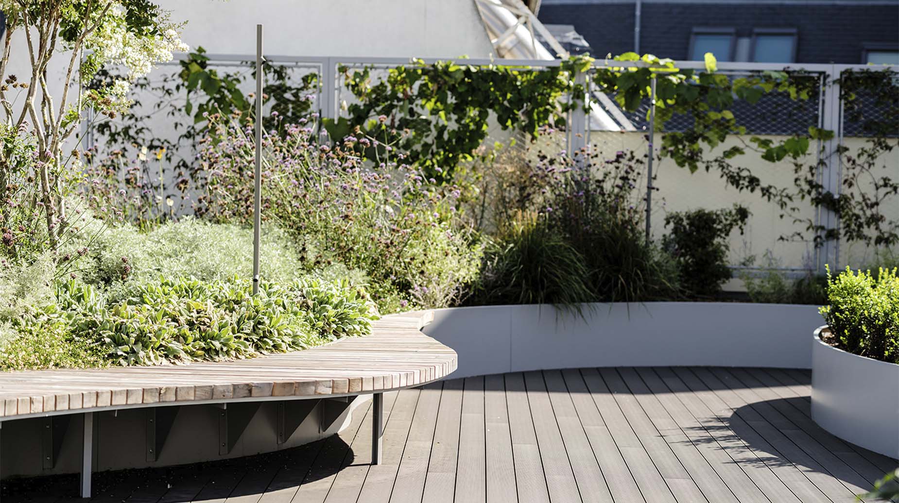 Daktuin met houten zitbank, plantenbakken en beplanting op een terras.