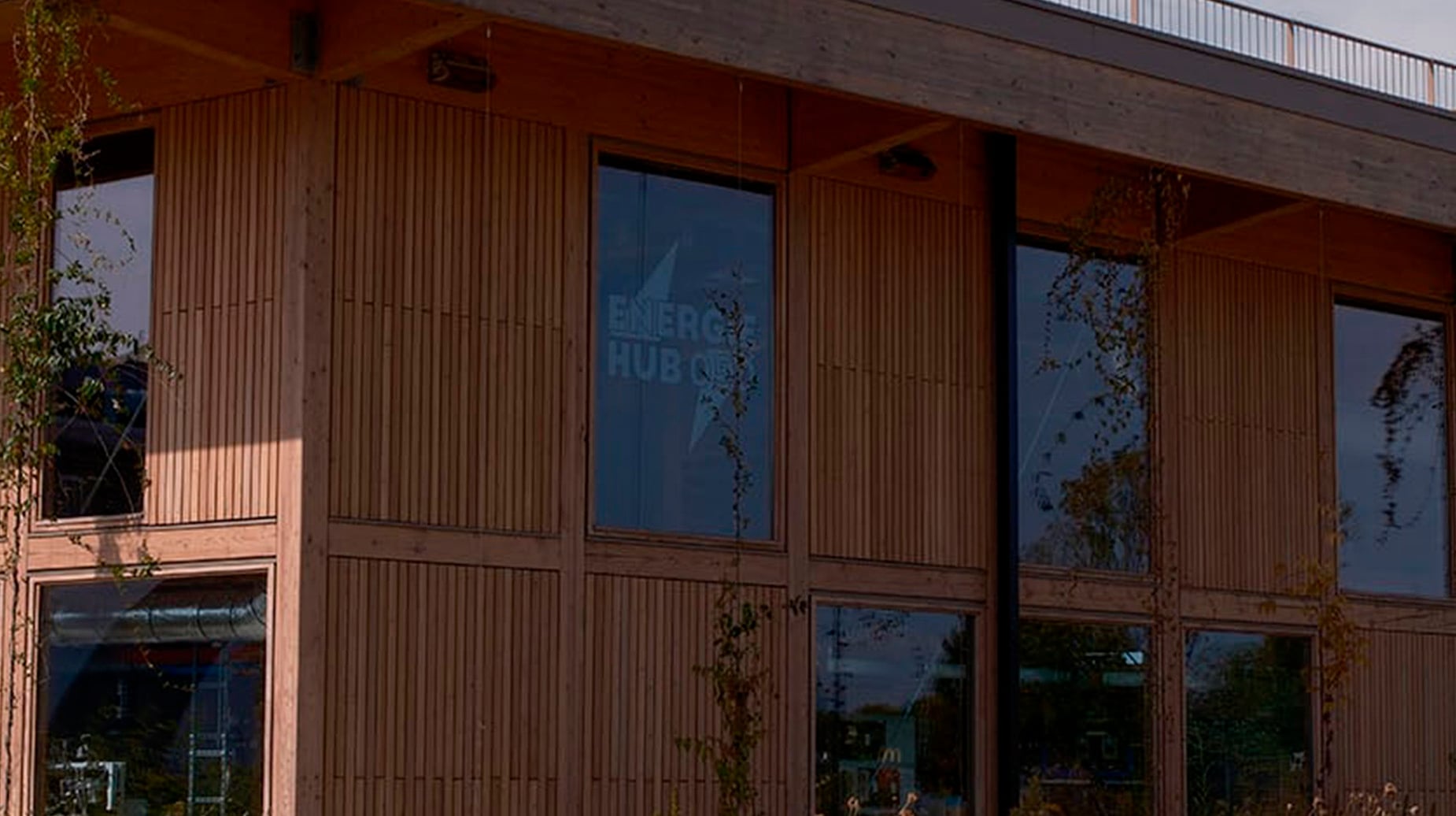 Houten gevel van Energie Hub met jonge beplanting langs de voorzijde van het gebouw.
