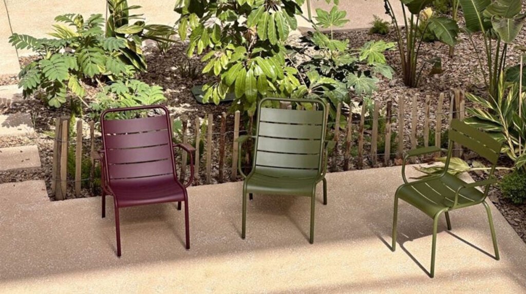 Metalen tuinstoelen op terras bij beplanting met houten afscherming.